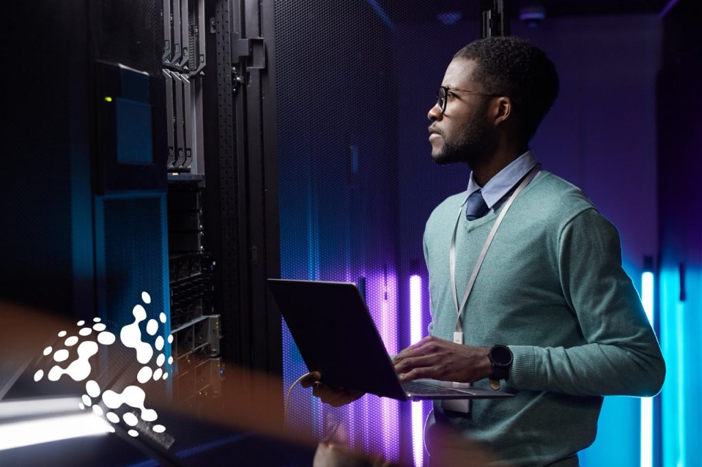 Young Guyanese IT professional using a laptop in a modern data center, symbolizing Guyana’s embrace of AI and technology-driven economic development.